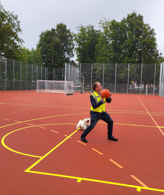 Bürgermeister Müller mit einem Basketball in der Hand auf dem neuen Allwetterplatz | © Stadt Geretsried