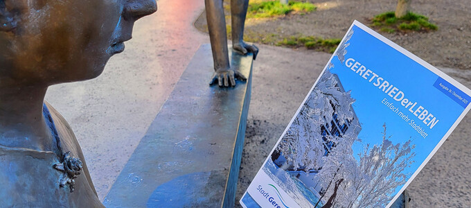 Statue einer lesenden Frau hält die neue Ausgabe des Stadtblattes in der Hand | © Stadt Geretsried
