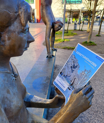 Statue einer lesenden Frau hält die neue Ausgabe des Stadtblattes in der Hand | © Stadt Geretsried