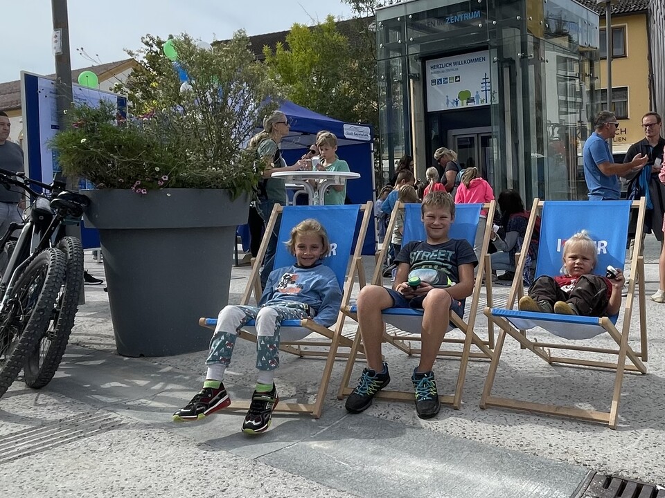 Drei Kinder sitzen auf blauen Liegestühlen beim Mobilitätsfest | © Stadt Geretsried