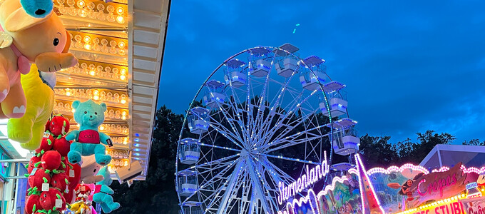 Menschen abends am Volksfest im Hintergrund das beleuchete Riesenrad | © Stadt Geretsried