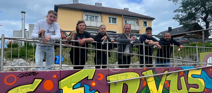 Gruppe mit Bürgermeister steht vor dem Graffiti-Schriftzug "Servus" | © Stadt Geretsried
