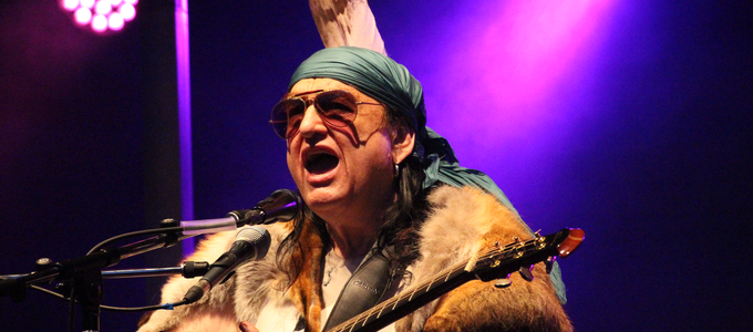 Isar-Indianer Willy Michl mit Federschmuck und Sonnenbrille auf der Bühne | © Stadt Geretsried