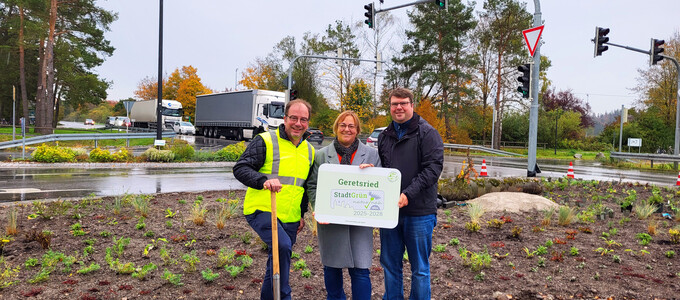 Die Gruppe steht vor der Verkehrsinsel und hält das Label StadtGrün naturnah in Silber | © Stadt Geretsried