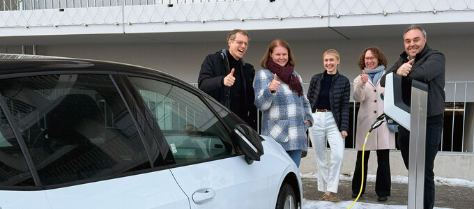 Die Gruppe steht neben dem E-Auto an der Ladesäule in der Banater Straße | © Krämmel GmbH