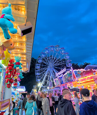 Waldsommer 2025 | © Stadt Geretsried Menschen abends am Volksfest im Hintergrund das beleuchete Riesenrad | © Stadt Geretsried